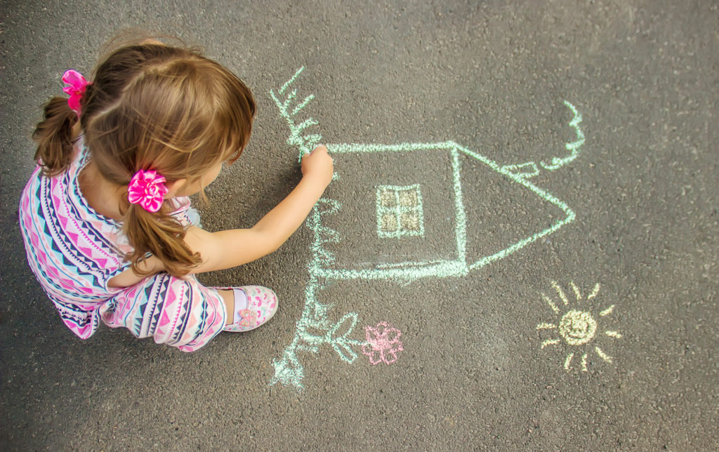 young girl draw a house on the floor